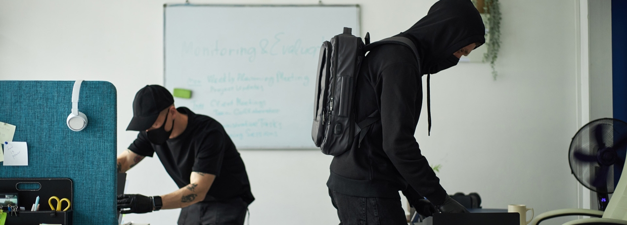 Twee inbrekers in zwarte kleding doorzoeken een kantoor